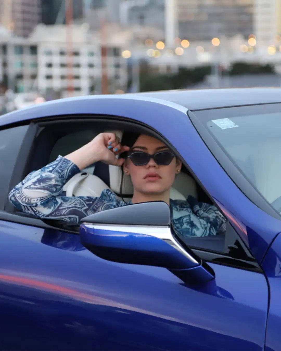 Woman wearing blue and white high fashion shirt, and sunglasses sitting in a Lexus, showcasing professional styling and product photography, work by Totally Digital Agency Auckland for client Shopify Marketing