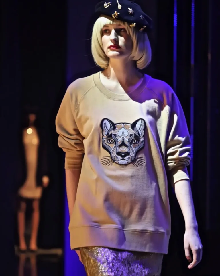 Woman walking down fashion runway with lion sweatshirt, wearing a beret on blond bob showcasing professional styling and product photography, work by Totally Digital Agency Auckland for client Shopify Marketing
