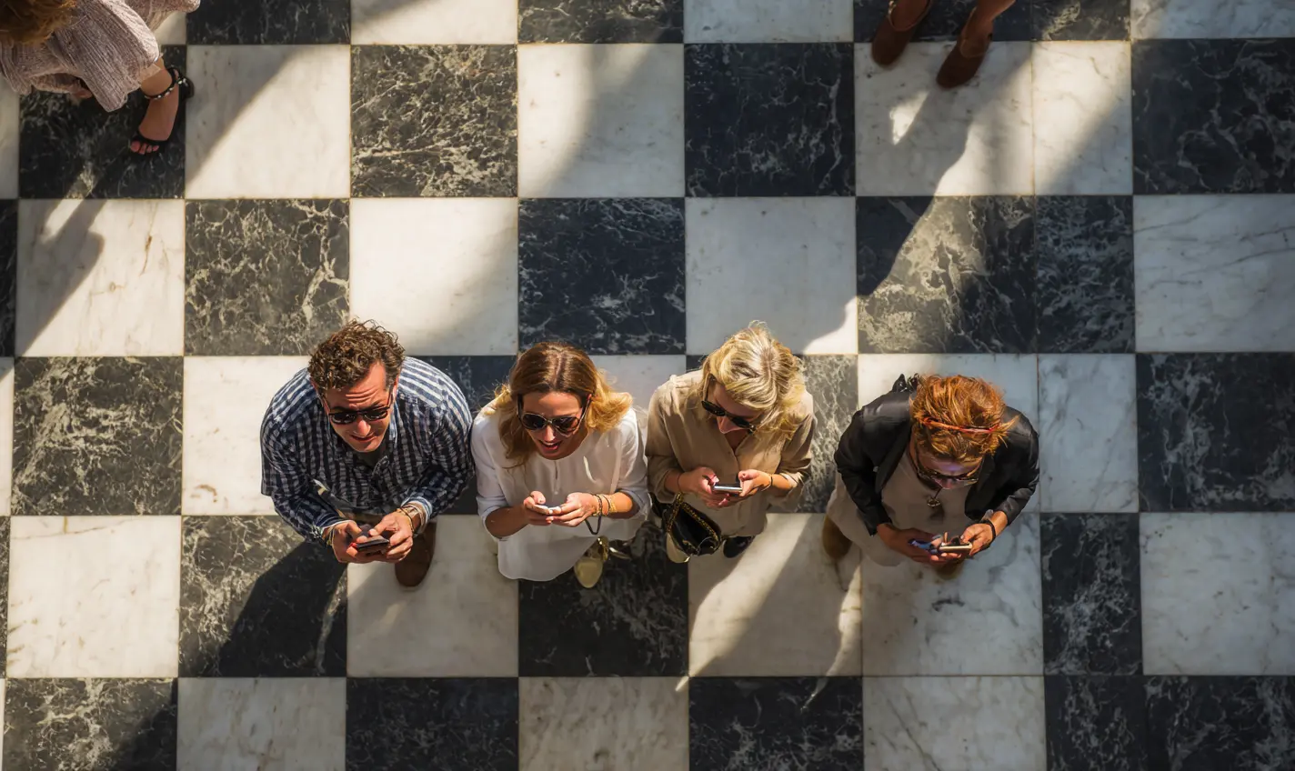 UX UI Design showing four people using their phones trying to get somewhere, standing on a checkered floor